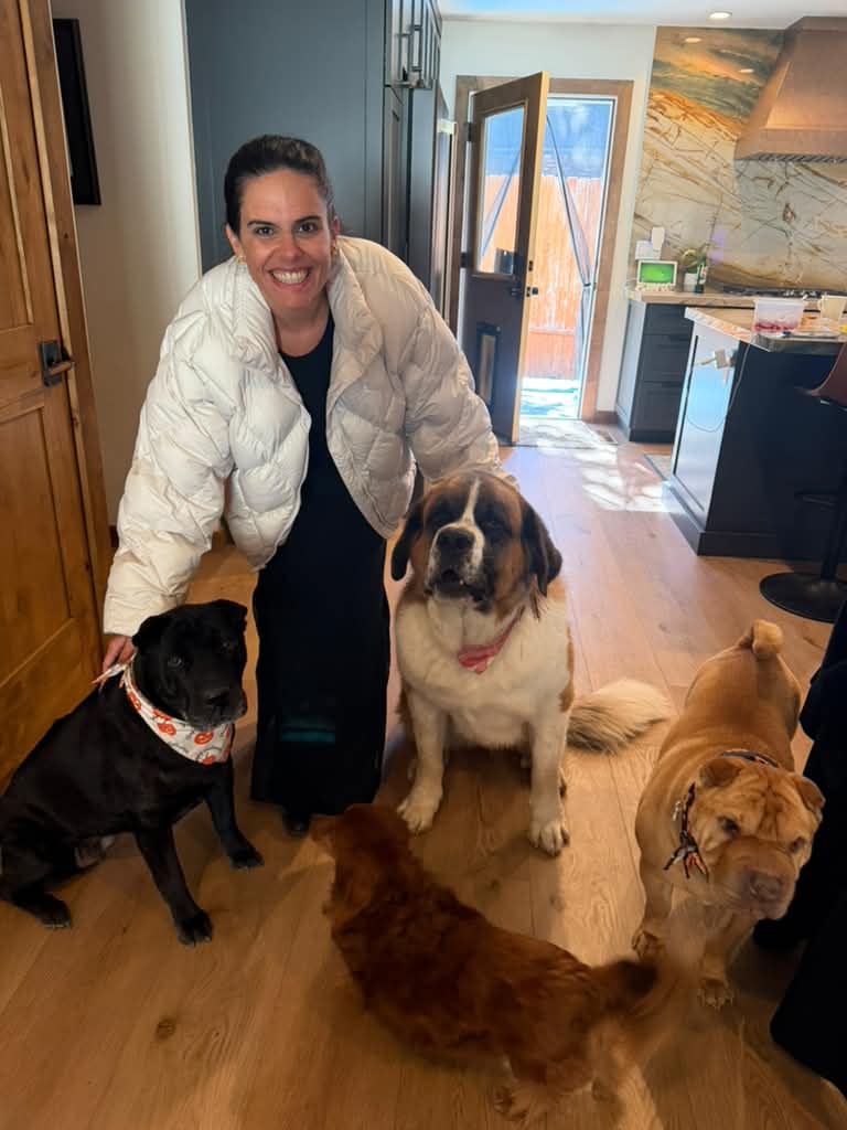 Claudia smiling with four dogs in a client's kitchen